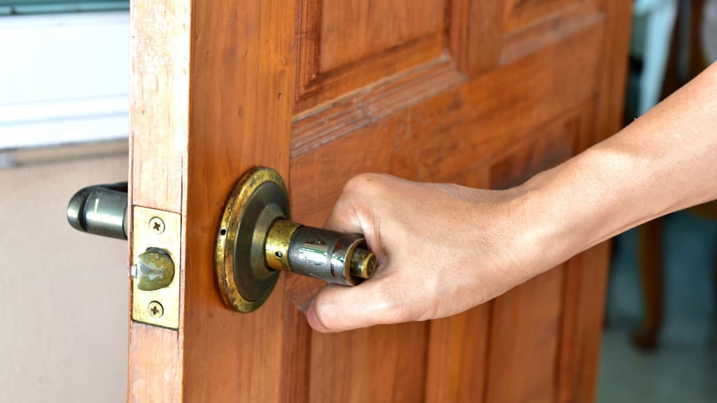 A person opening an out-swing exterior door